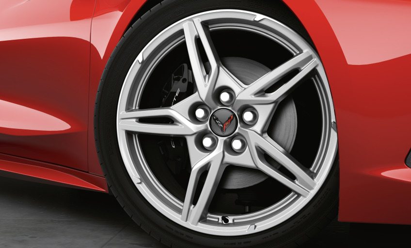 Aluminiumfelge einer Chevrolet Corvette C8 Stingray Nahaufnahme einer silbernen Aluminiumfelge mit Corvette-Emblem an der roten Chevrolet Corvette C8 Stingray.