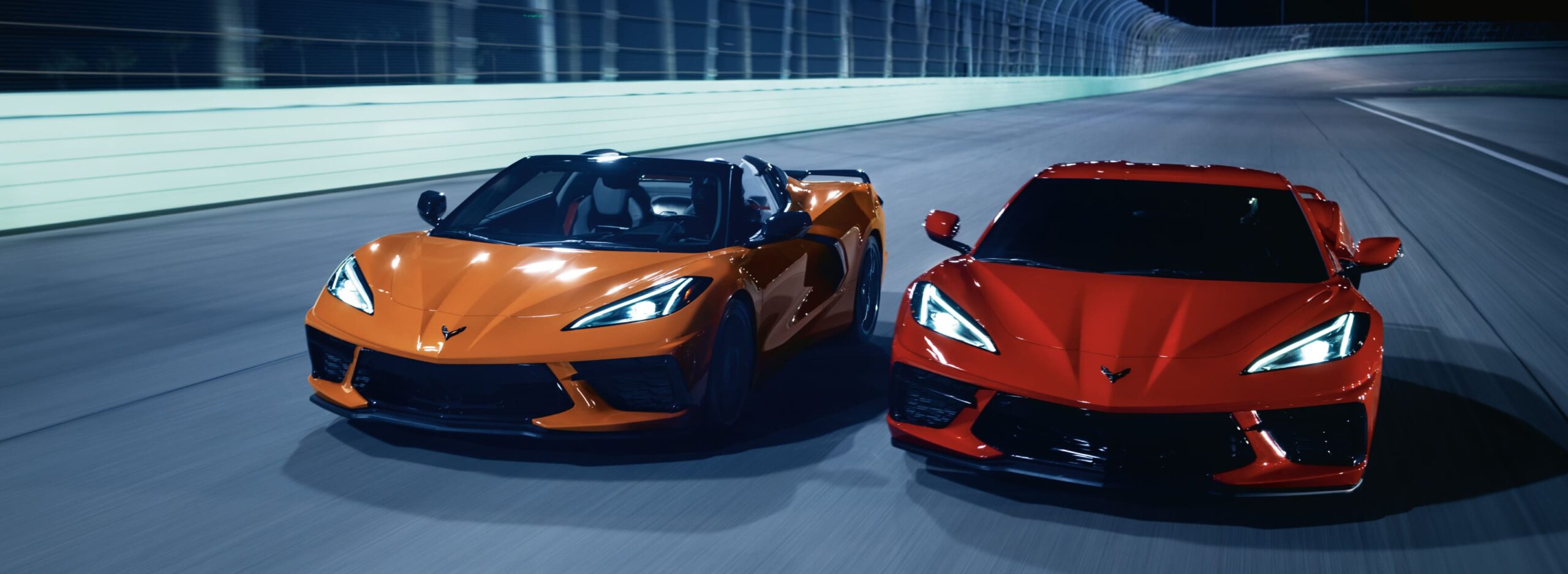 Corvette C8 Stingray - Rennstrecke Zwei Chevrolet Corvette C8 Stingray fahren nachts nebeneinander auf einer beleuchteten Rennstrecke.