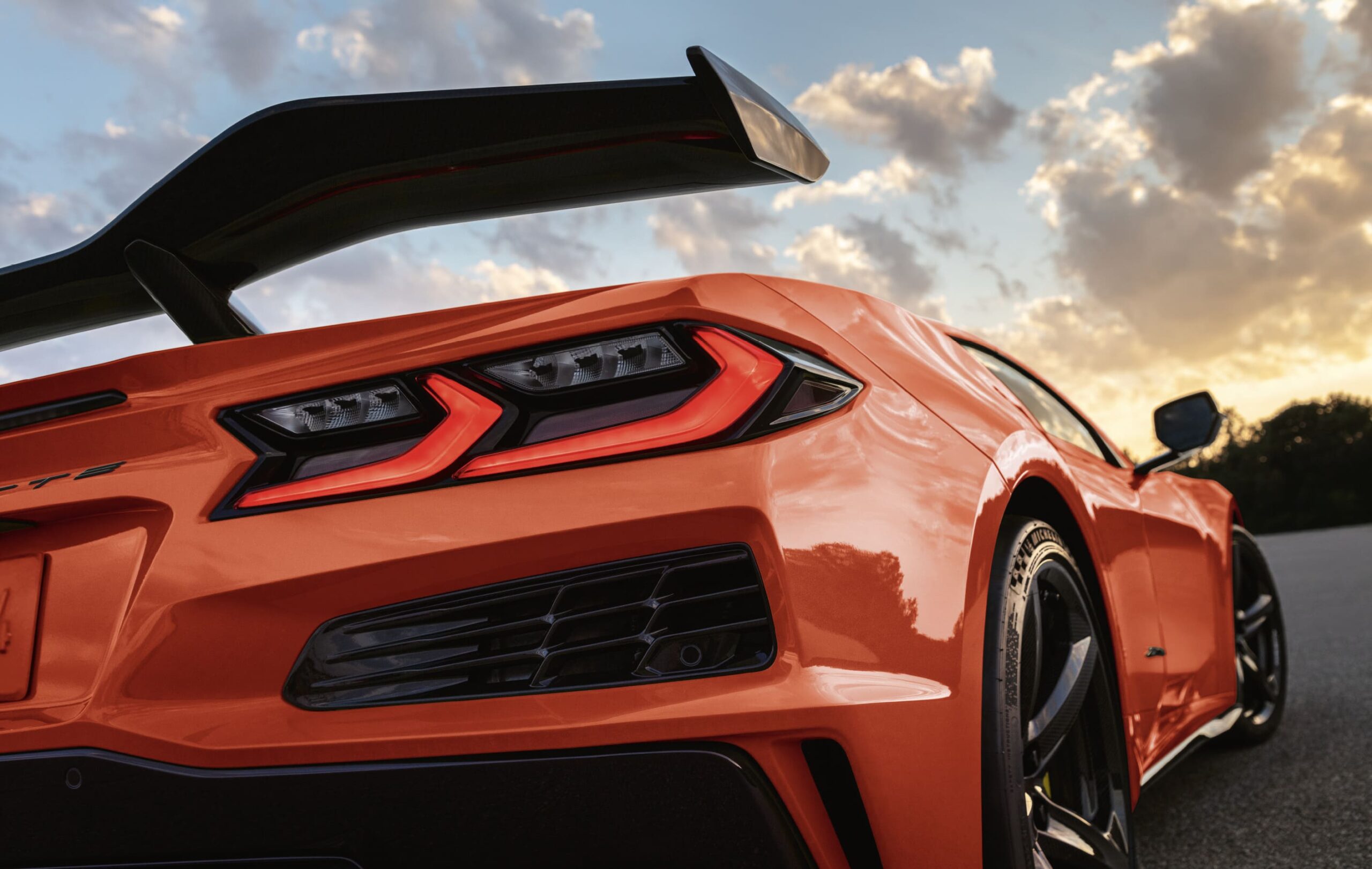 Corvette C8 Z06 - Autohaus Köhler in Potsdam Detailansicht des Hecks einer orangefarbenen Chevrolet Corvette Z06 mit großem Heckspoiler bei Sonnenuntergang.